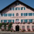 Gasthof zur Post.jpg Großes rosa Haus mit Blumen an Fenstern. Blaue Läden geben freundliche Wirkung.