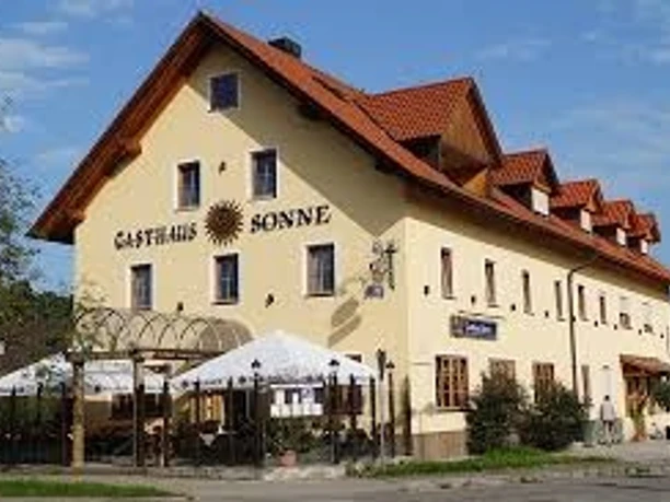Gasthof Sonne.jpg Großes gelbes Gasthaus mit rotem Dach und hellem Biergarten vor dem Haus.