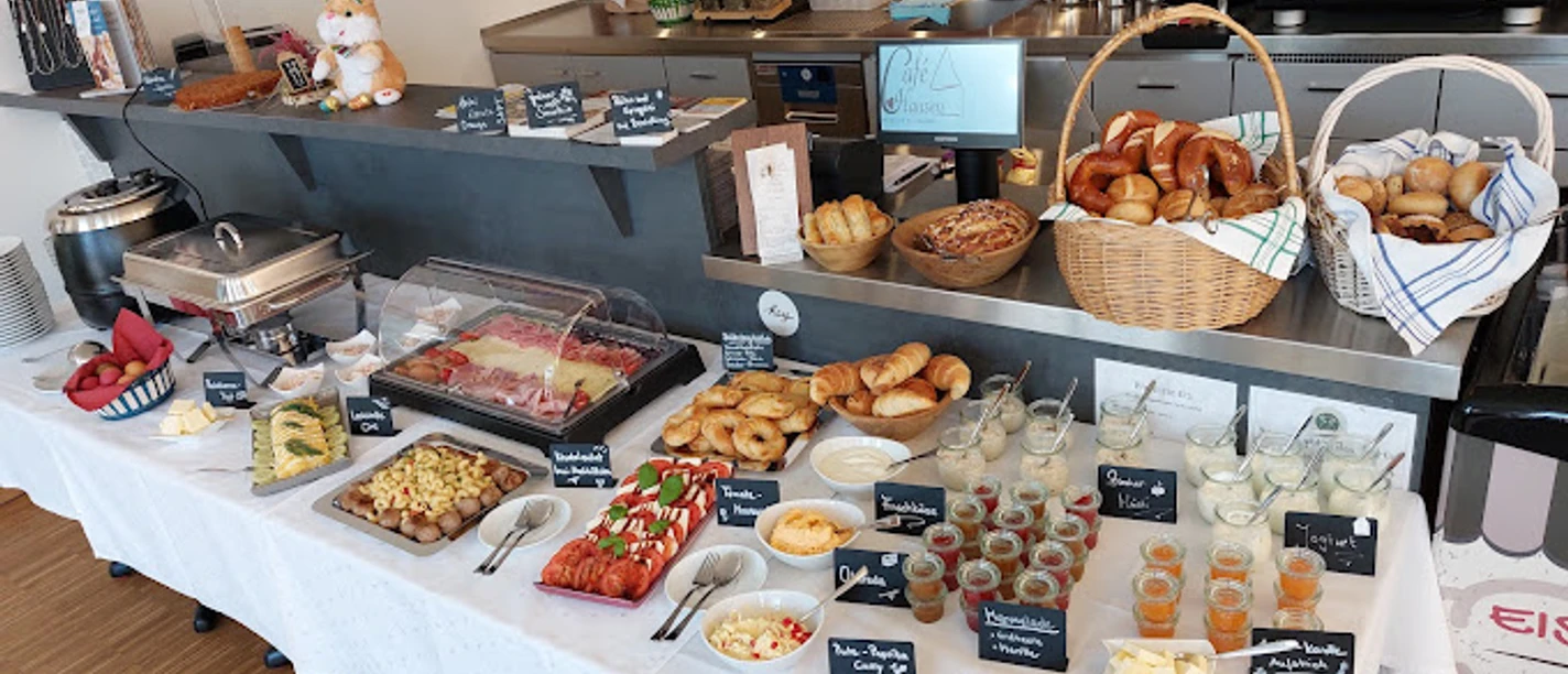 Cafe Hausen Frühstücksbuffet mit Brot, Obst, Käse und vielen kleinen Gläsern mit Speisen.