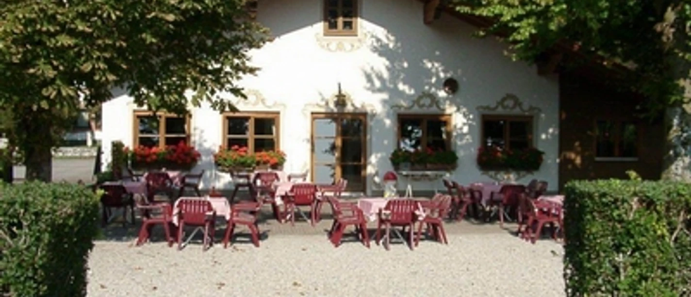 Rigi Alm Helles Haus mit vielen Tischen unter Bäumen lädt zu Pause auf Reise ein.