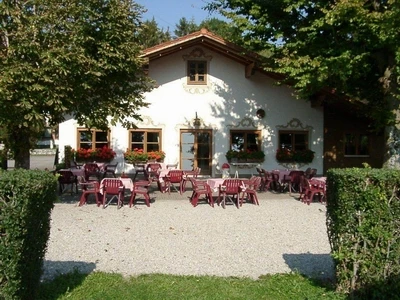 Rigi Alm Helles Haus mit vielen Tischen unter Bäumen lädt zu Pause auf Reise ein.