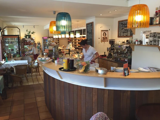 Cafe Sesar Helles Café mit Theke, bunten Lampen und vielen Backwaren im beliebten Raum.