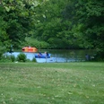 bremerhaven_erlebnis_tretboot 07 (c) Andreas Larmann.jpg Menschen fahren in bunten Tretbooten über einen kleinen See, umgeben von dichtem grünen Bäumen.