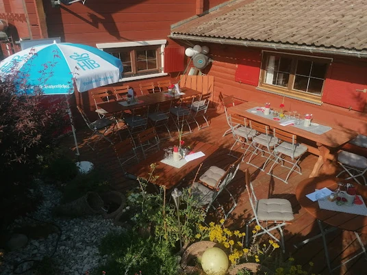 Schneidlbergstuben Holzterrasse mit Tischen und Stühlen lädt zu einer Pause ein.