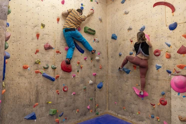 Zwei Personen klettern an einer bunten Boulderwand in der Kletterhalle Bremerhaven.