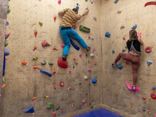 IMG_9215 (c) Hannes Voigts_Erlebnis Bremerhaven.jpg Zwei Personen klettern an einer bunten Boulderwand in der Kletterhalle Bremerhaven.