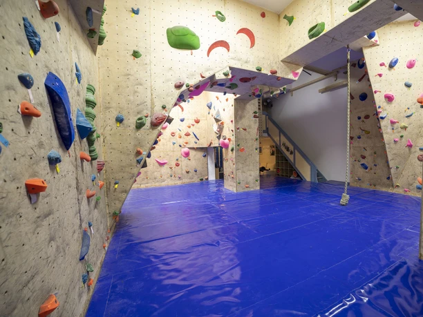 IMG_9329 (c) Hannes Voigts_Erlebnis Bremerhaven.jpg Innenraum einer Kletterhalle mit bunten Griffen, blauen Matten und Seil zum Training an der Wand.