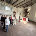 Gästeführung vor dem Altar der Kirche Gruppe in der St.-Ulrichs-Kirche betrachtet den Altarraum mit bunt leuchtenden Kirchenfenstern.