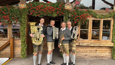 Hinterberger-Musikanten-2026.jpg Vier Hinterberger Musikanten in Tracht vor festlicher Almhütte
