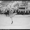Sonja Henie bei den Olympischen Winterspielen Eiskunstläuferin springt vor winterlicher Bergkulisse auf einer großen Freiluftbahn.Figure skater jumping in front of a wintry mountain backdrop on a large outdoor rink.