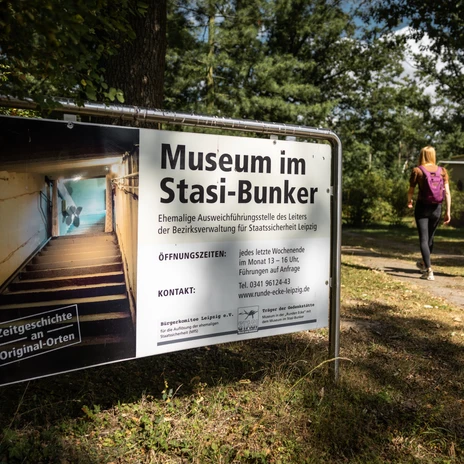 Panneau d'entrée du bunker de la Stasi à Machern sur un fond boisé.