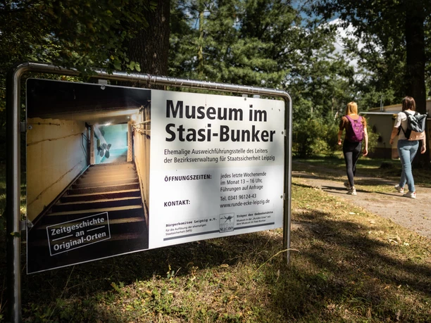 Panneau d'entrée du bunker de la Stasi à Machern sur un fond boisé.