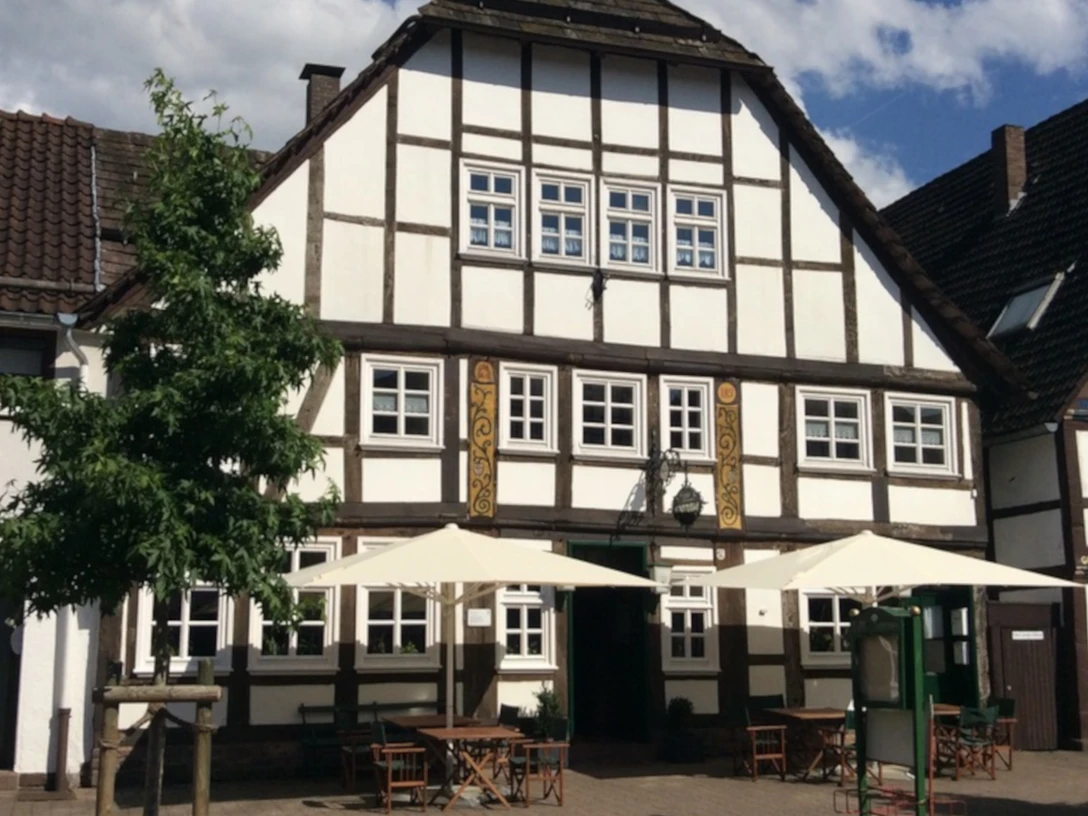 Stadtkrug Fachwerkhaus mit Außenbestuhlung und hellen Sonnenschirmen im Vordergrund.