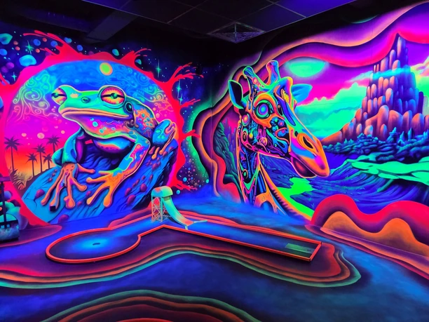 Bunte Schwarzlicht-Minigolfbahn mit leuchtenden Wandmalereien von Frosch und Giraffe in Neonfarben.