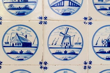Een groep mannen in witte matrozenhemden op een historische zeilboot voor een bakstenen gebouw met het opschrift 'FEHN- UND SCHIFFFAHRTSMUSEUM'