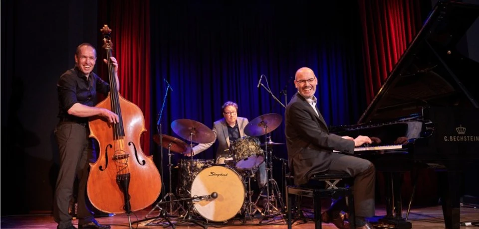 Frank Muschalle Trio Drei Musiker auf Bühne mit Kontrabass, Schlagzeug und Flügel bei Blueskonzert.