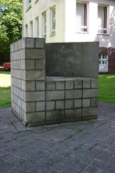 Skulpturen - Zwei gleichgroß Zweiteilige Betonskulptur aus grauen Quadern, modern platziert im Grünen vor einem Gebäude.