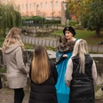 Stadtführung - Hann. Münden Marketing GmbH - Jules Stolzenhain-54.jpg Eine Frau in historischem Kostüm führt eine Gruppe auf einer Stadtführung im Freien an.