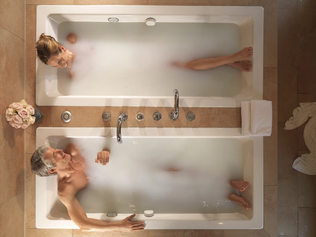 Gräflicher Park Bad Driburg Spa Zweisam genießen.jpg Ein Paar liegt im Gräflichen Park Bad Driburg im Spa Bereich in zwei Badewannen und lächelt sich an