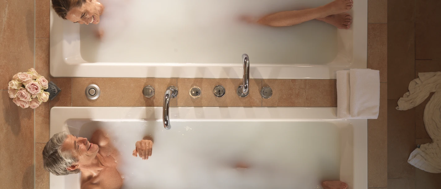 Gräflicher Park Bad Driburg Spa Zweisam genießen.jpg Ein Paar liegt im Gräflichen Park Bad Driburg im Spa Bereich in zwei Badewannen und lächelt sich an