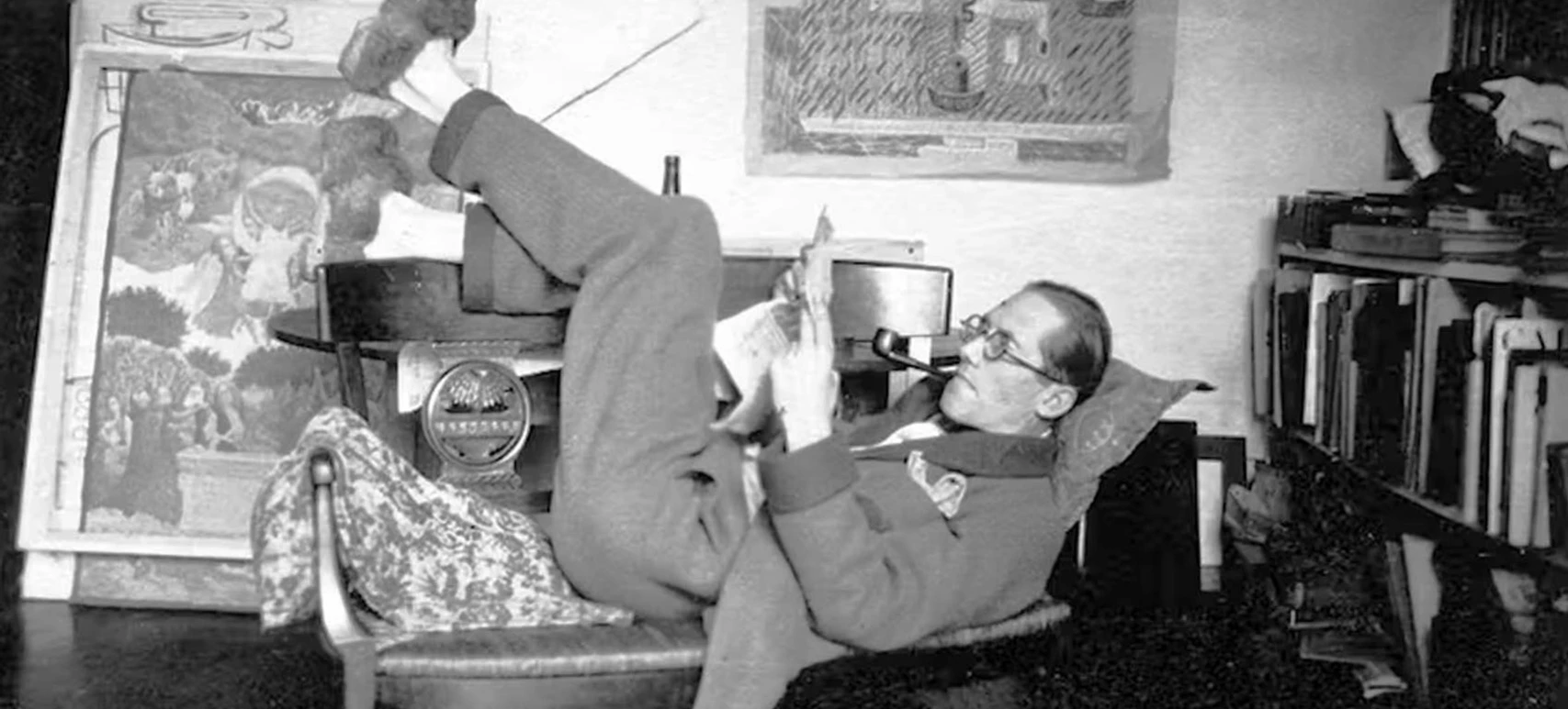 LC-la-rue-Jacob Mann liest mit Pfeife auf Liege in Atelier umgeben von Büchern und Kunstwerken.Man reading with a pipe on a lounger in a studio surrounded by books and works of art.