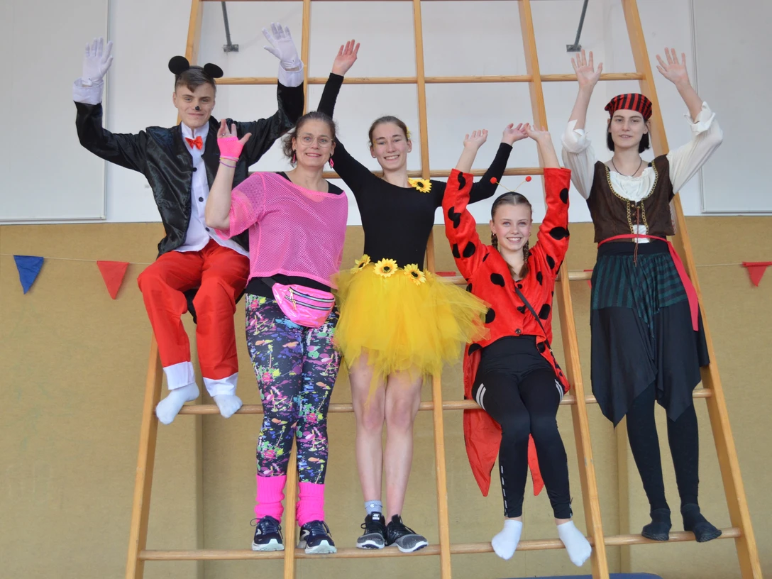 Kinderkarneval in der Kleinen Halle Feldbreite Fünf kostümierte Kinder und Jugendliche posieren fröhlich auf einer Turnleiter beim Kinderkarneval.