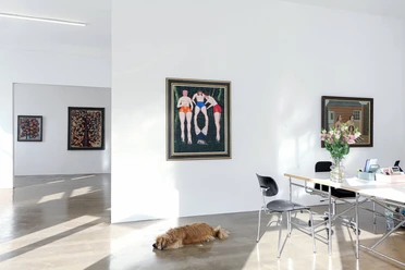 Zander Collection Cologne Bright gallery room with paintings, work table with flowers and resting dog on the floor.