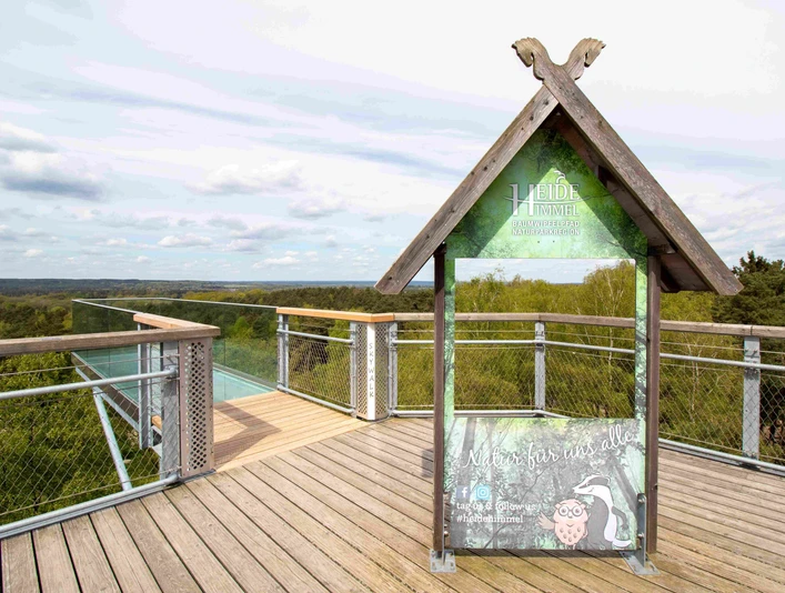 SkywalkTigerblickII2024.jpg Aussichtsplattform mit Holz- und Glaselementen über den Baumwipfeln am barrierefreien Baumwipfelpfad Heide Himmel.