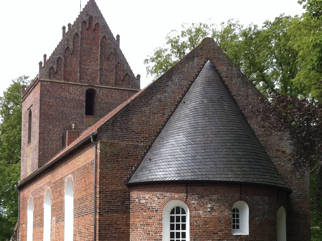 St. Laurentius- und St. Vincentius-Kirche Backemoor.JPG Backsteinkirche mit romanischem Rundturm und gotischem Giebel, umgeben von Bäumen