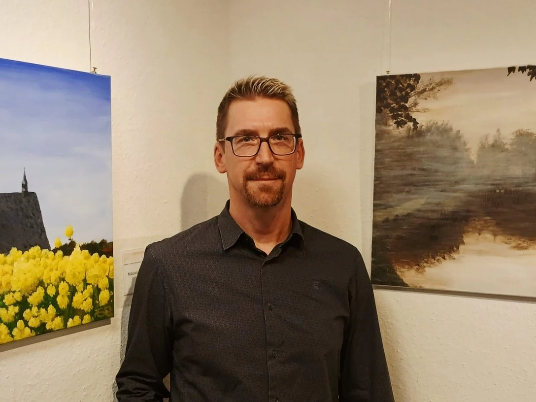 Andreas Rätsch Geithain Künstler Andreas Rätsch steht in einer Ausstellung vor seinen Bildern.