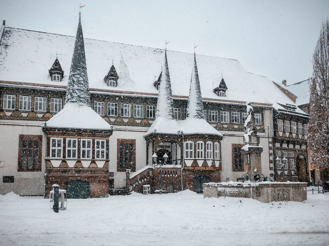 Altes Rathaus im Winter Historisches Fachwerkhaus im Schneefall mit verschneiten Türmen und Brunnen auf einem winterlichen Platz