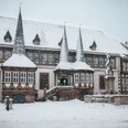 Altes Rathaus im Winter Historisches Fachwerkhaus im Schneefall mit verschneiten Türmen und Brunnen auf einem winterlichen Platz