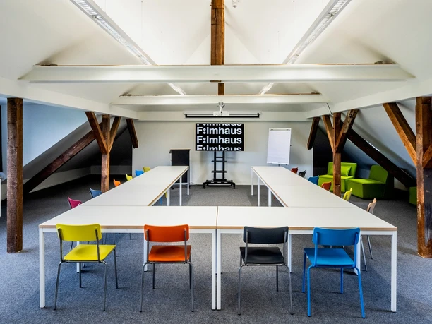 Filmhaus, Seminarraum Ein Dachgeschossraum mit einer U-Form Bestuhlung mit Tischen.