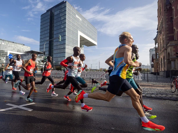 Köln Marathon Running group in the Cologne Marathon in front of modern buildings on a wet road in dynamic movement