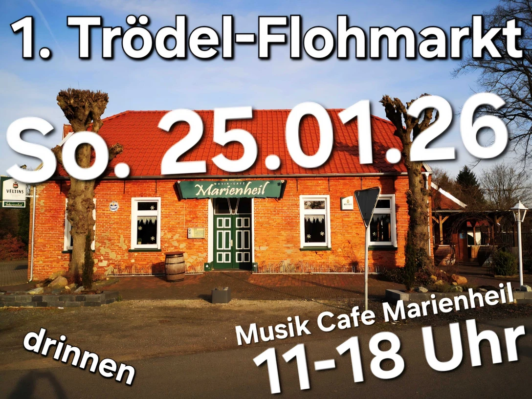 Flohmarkt.jpg Backsteingebäude mit grünem Eingangsschild 'Marienheil' und rotem Dach vor blauem Himmel