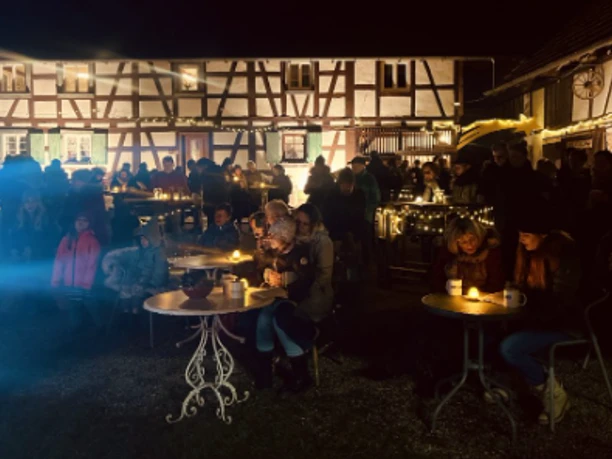 beleuchteter Hof mit Menschen an Tischen beim Singen auf dem Schollenhof Wagshurst