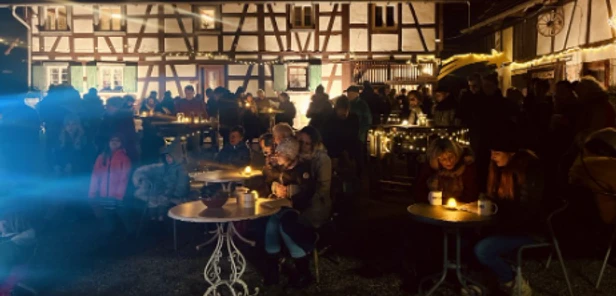 beleuchteter Hof mit Menschen an Tischen beim Singen auf dem Schollenhof Wagshurst