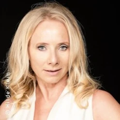 Porträt einer blonden Frau vor dunklem Hintergrund