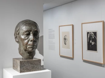 Käthe Kollwitz Museum Bronze bust on a plinth in front of two framed portraits in a bright museum gallery