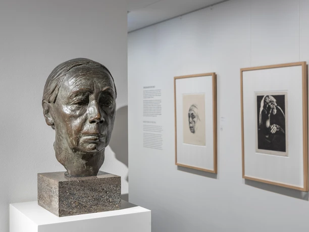 Käthe Kollwitz Museum Bronze bust on a plinth in front of two framed portraits in a bright museum gallery