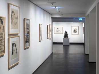 Käthe Kollwitz Museum Bright museum corridor with framed drawings on the walls and a sculpture at the end