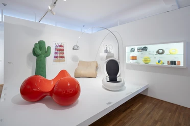 Museum of Applied Arts Cologne Exhibition room with colorful design objects such as red seating furniture, cactus figure and retro chair.