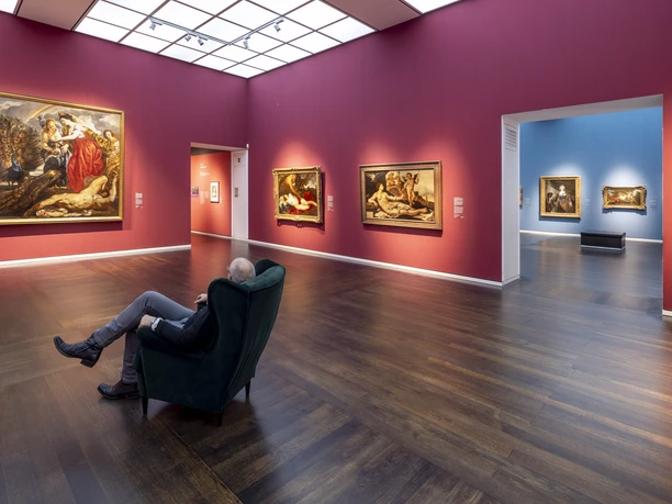 Wallraf-Richartz-Museum Gallery with large-format paintings and a seated person in front of colorful walls.