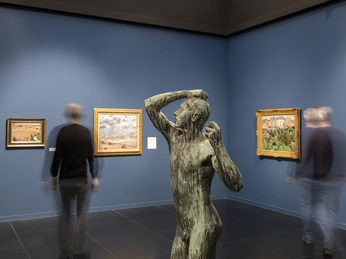 Wallraf-Richartz-Museum Gallery space with bronze figure in the foreground, surrounded by paintings and passing visitors