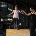 First steps in balancing A trainer holds a girl's hand and gives assistance on a roll in the Aletsch Arena hands-on circus.