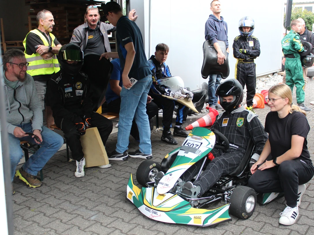 Bild 3_2025-08-31_ MSC-SHS_Vorstart_Klasse 4_Maxi Lutz_letzte instruktion Trainerin Cora Kortrenkamp.JPG Jugendlicher im Kart vor dem Start, Trainerin gibt letzte Hinweise, weitere Teilnehmende warten.