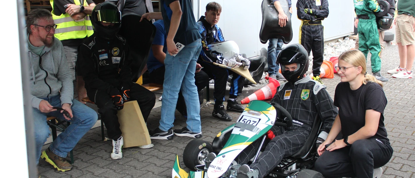 Bild 3_2025-08-31_ MSC-SHS_Vorstart_Klasse 4_Maxi Lutz_letzte instruktion Trainerin Cora Kortrenkamp.JPG Jugendlicher im Kart vor dem Start, Trainerin gibt letzte Hinweise, weitere Teilnehmende warten.