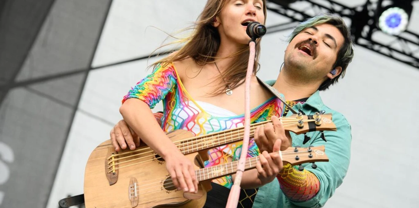 Kultur-Gulfhof-Freepsum: Duo Ronja und Fede Zwei Musiker spielen gemeinsam Gitarre auf einer Bühne und singen mit geschlossenen Augen.