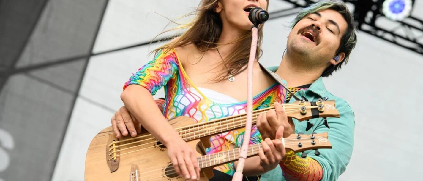 Kultur-Gulfhof-Freepsum: Duo Ronja und Fede Zwei Musiker spielen gemeinsam Gitarre auf einer Bühne und singen mit geschlossenen Augen.
