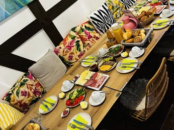 Tischbuffet (Frühstück) Frühstücksbuffet mit Brot, Käse, Aufschnitt, frischem Gemüse und Säften auf festlich gedecktem Tisch.